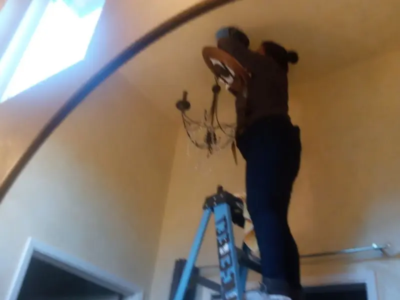 Electrician installing a chandelier in a Burnham residence